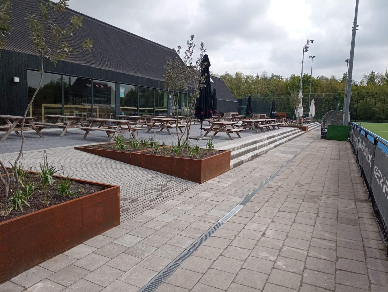 Buitenterras met plantvakken bij een sportclub — realisatie Jardim